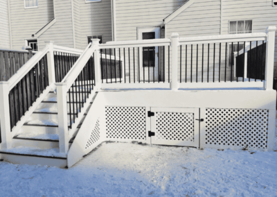 White low-maintenance deck with lattice bottom. Snow surrounding the deck