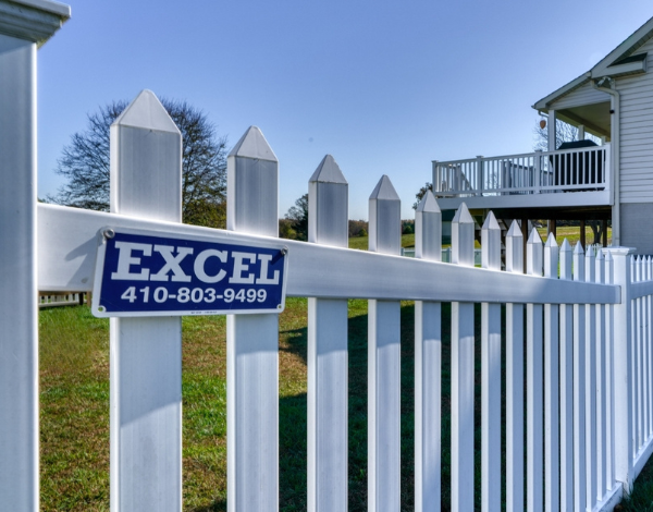 Blue excel sign on a white picket fence at Excel Fencing and Decking 