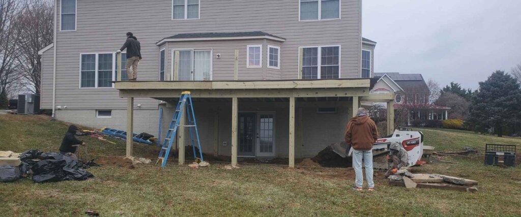 Backyard transformation showing site clearing and wood framing for a nine foot tall deck in Forest Hill MD